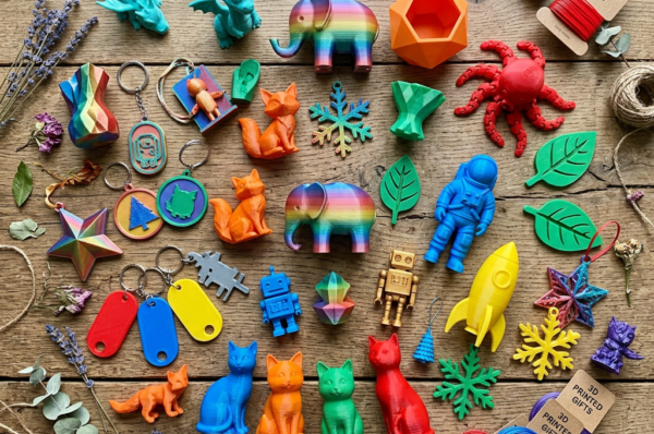 Colorful 3D-printed figures, ornaments, tags, and gifts on a wooden table